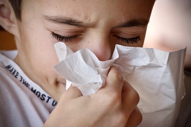 Picture of a child with a cold, blowing his nose