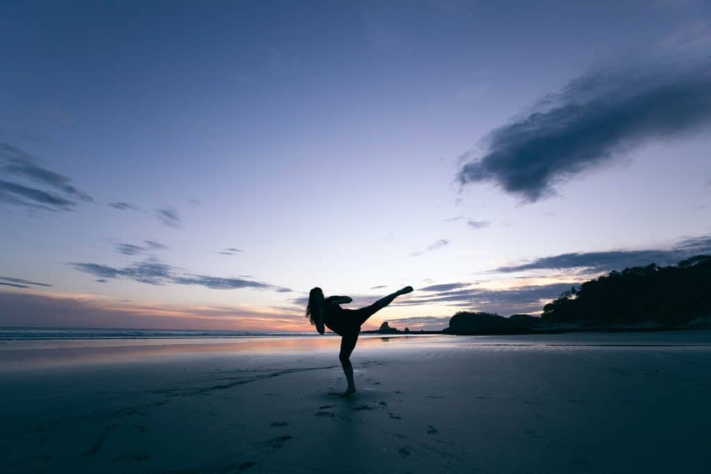 Woman practicing martial arts on the beach