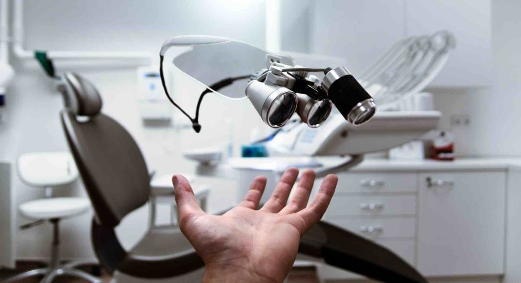 Man's hand pointing to a dental checkup chair