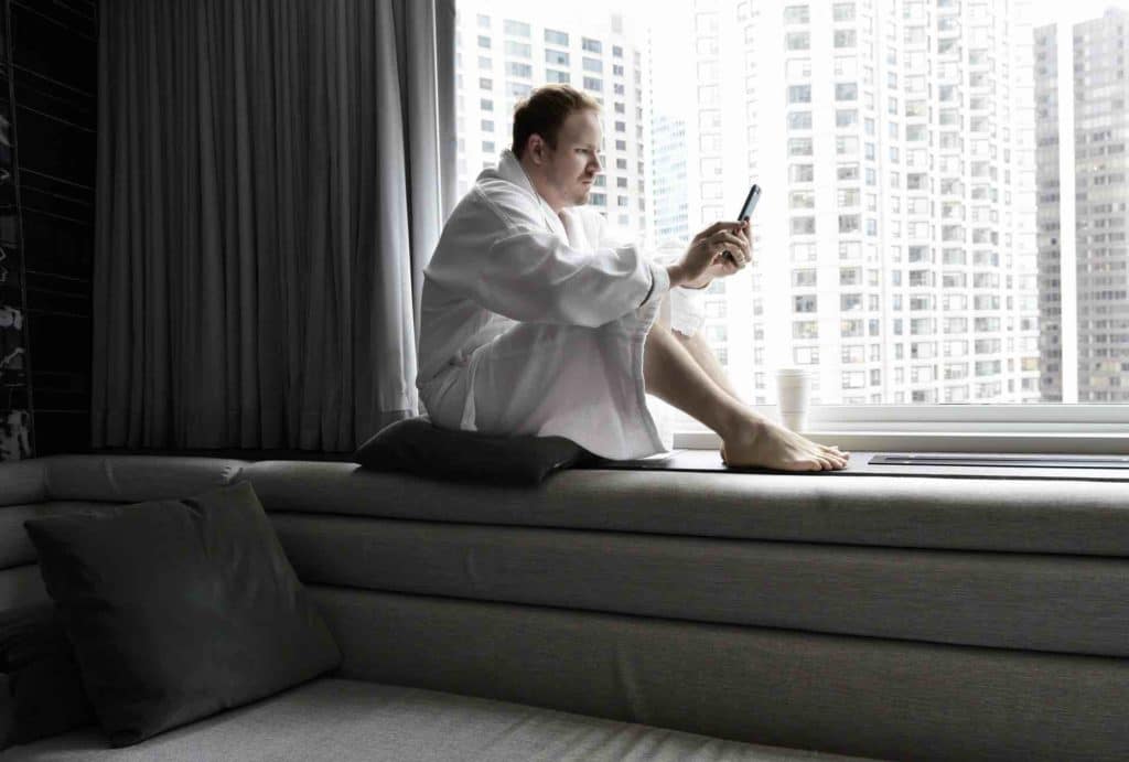 Man in a robe on his phone by the window