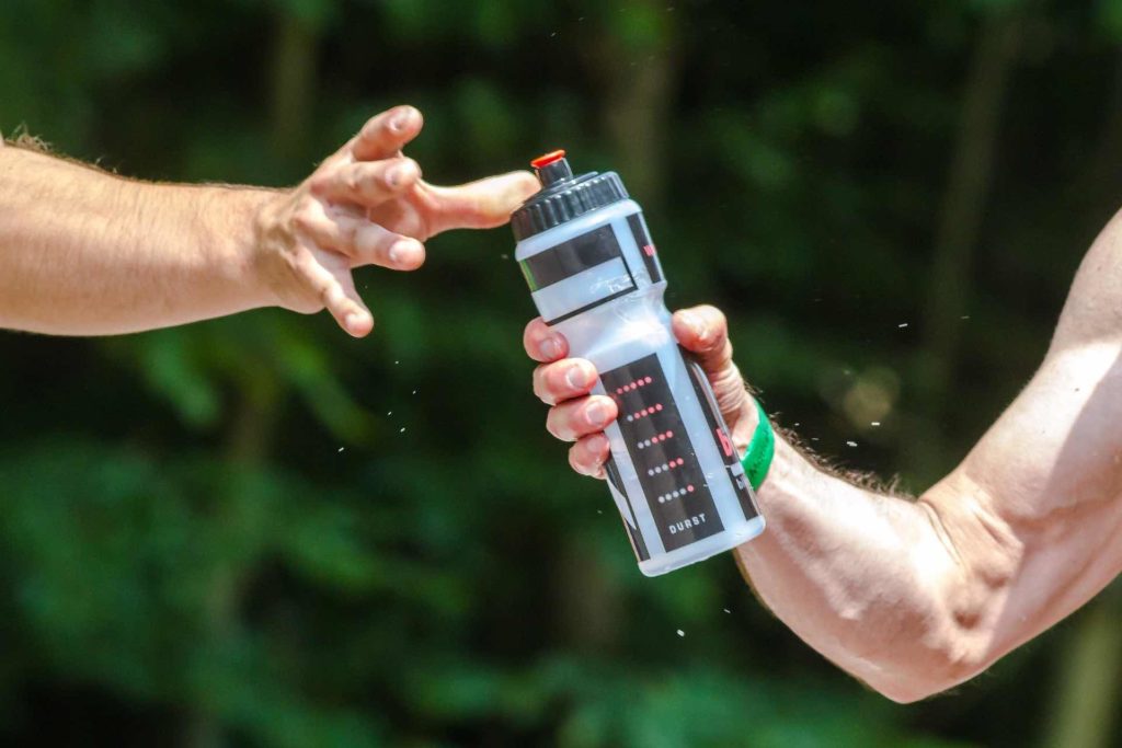 Runner handing a water bottle to another runner