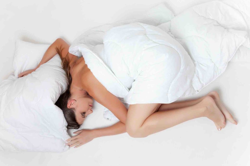 Woman sleeping uncomfortably in a bed