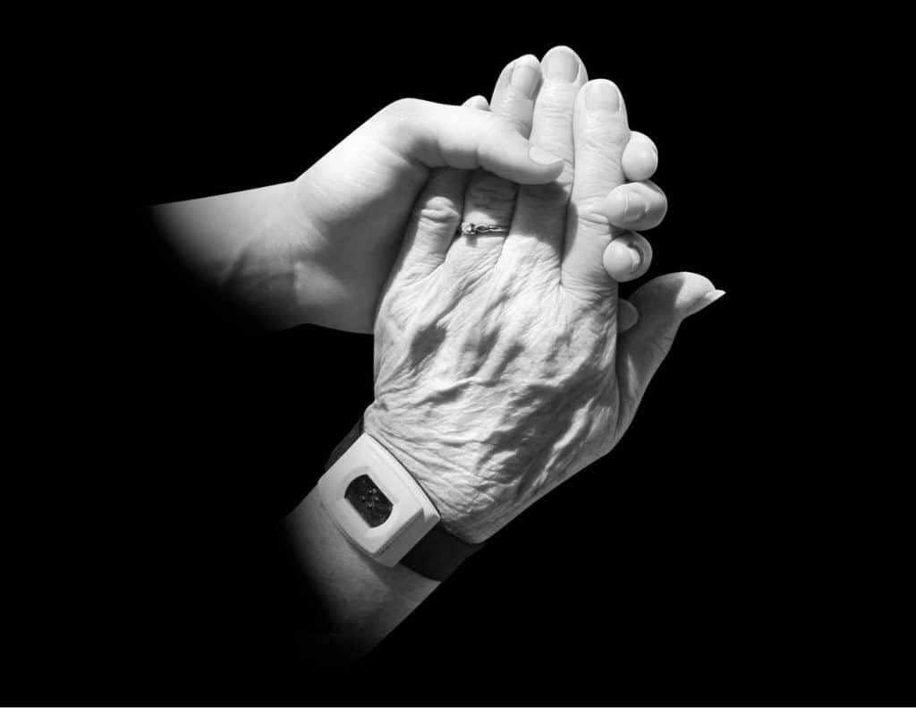 Younger hand holding an elderly person's hand