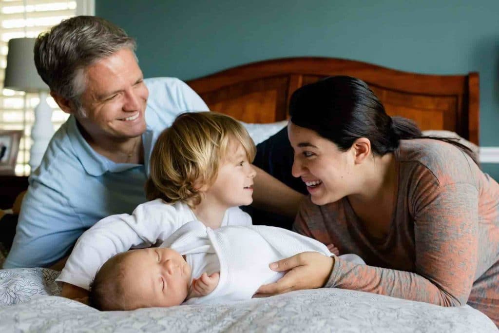 Mother, father, and two children laying on a bed smiling