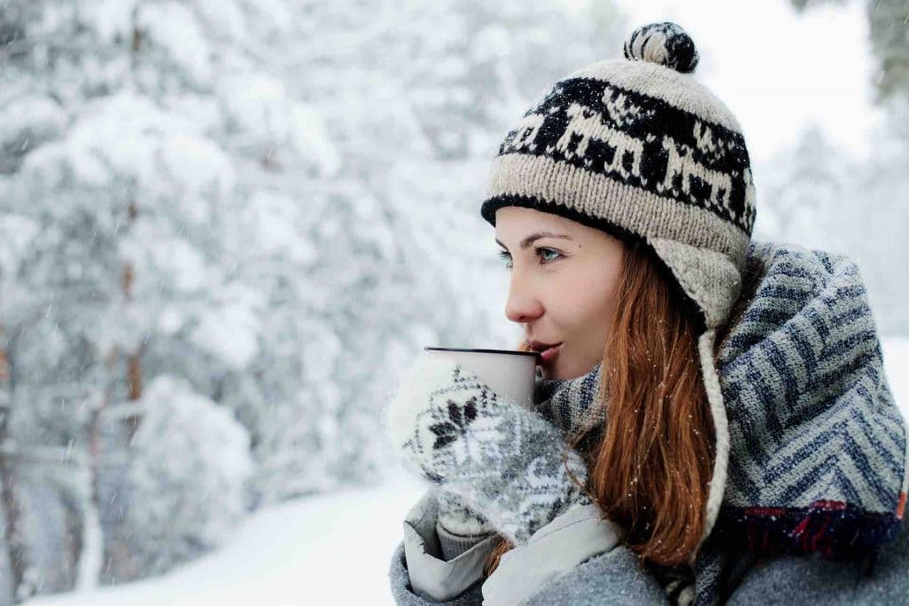 Woman standing in a snow flurry and drinking tea