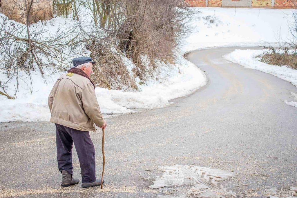 Elderly man walking with cane in the snow