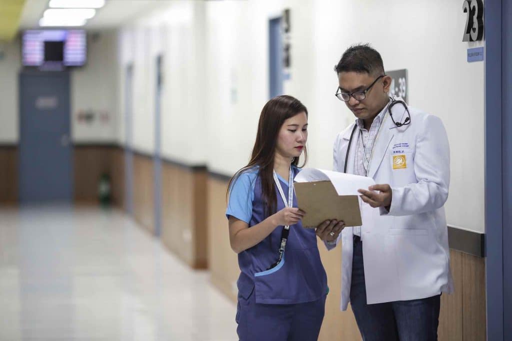 Doctor and assistant discussing medical records in a hallway