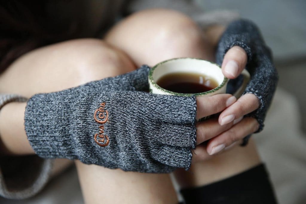 Woman wearing copper compression gloves and holding a cup of coffee