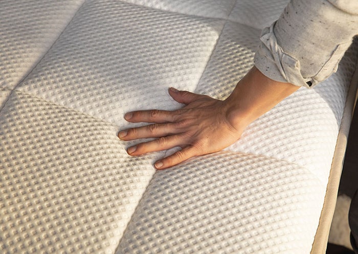 Hand pushing down on the top layer of a Dreamcloud bed