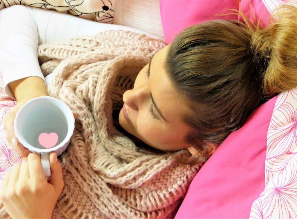 Woman with the flu resting and drinking hot tea
