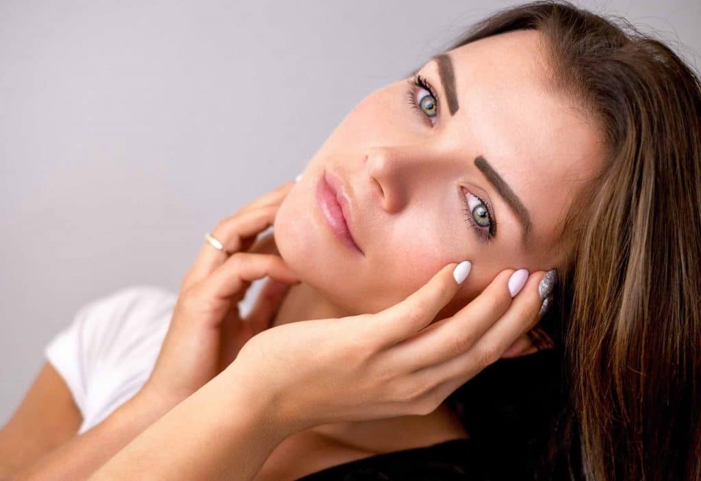 Woman with dermal fillers touching her face