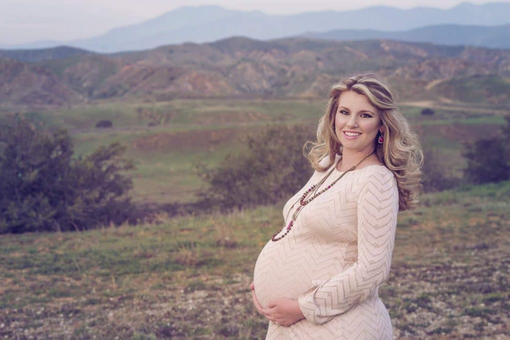Pregnant woman standing outdoors and smiling