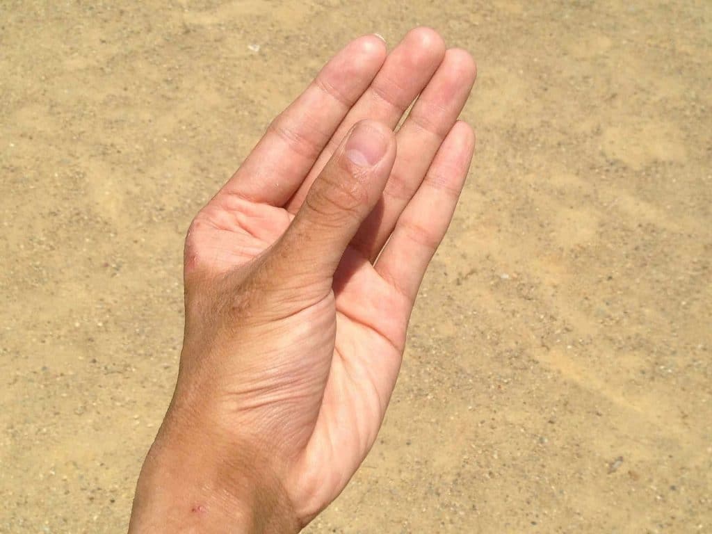 Man's dry hand with sand in the background