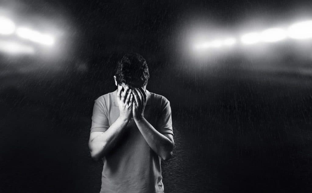 Man standing in the rain with his head in his hands