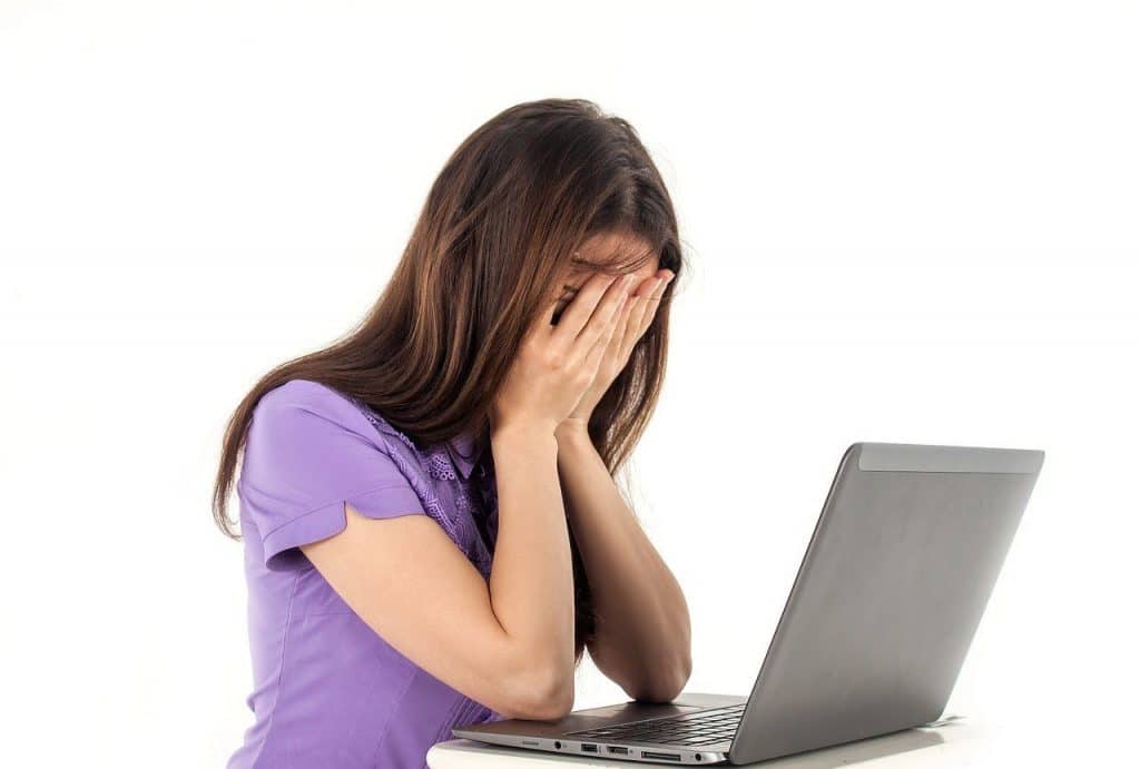 Stressed woman covering her face at a computer