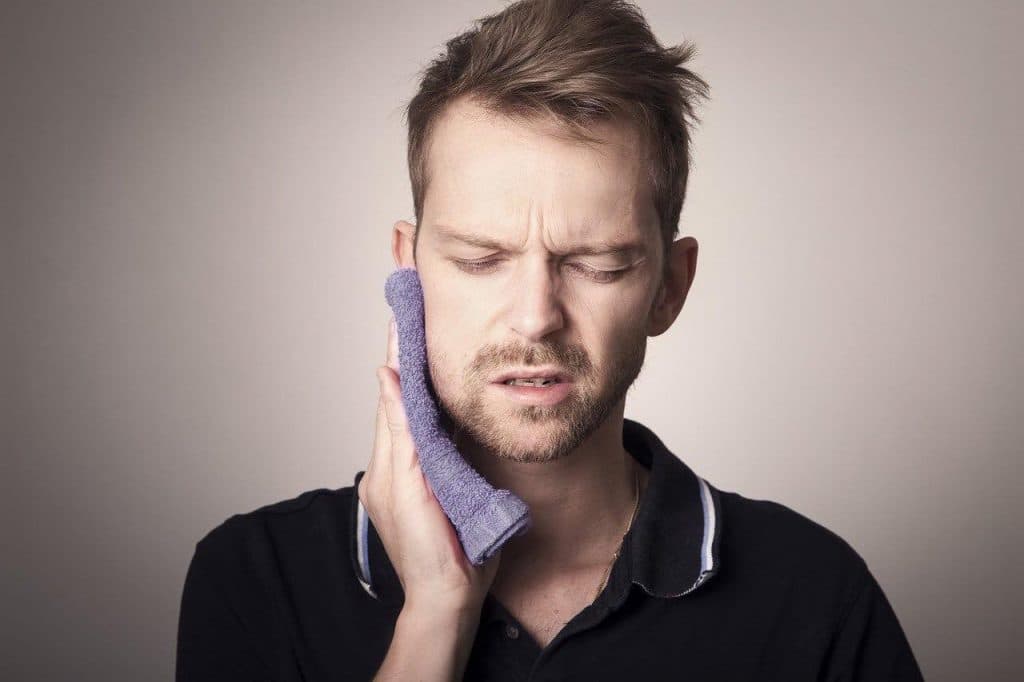Man with a toothache holding a warm towel to his face
