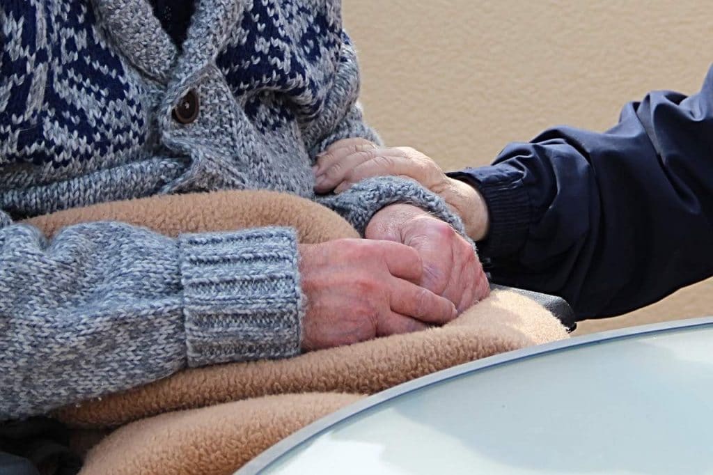 Elderly person sitting with a nurse holding their arm