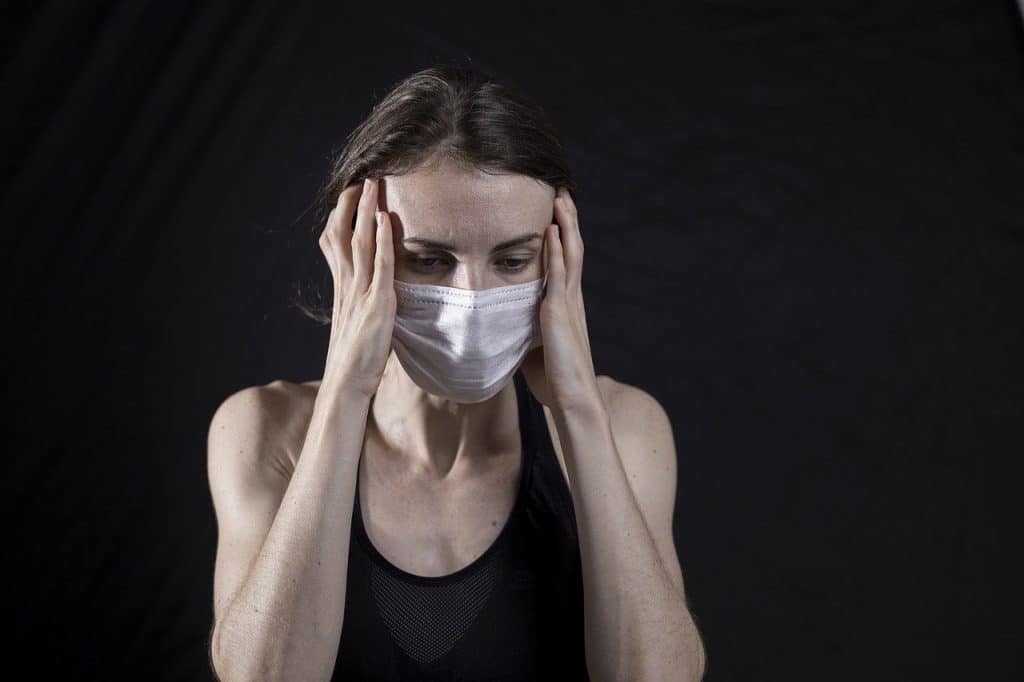 Woman wearing a mask who has a headache