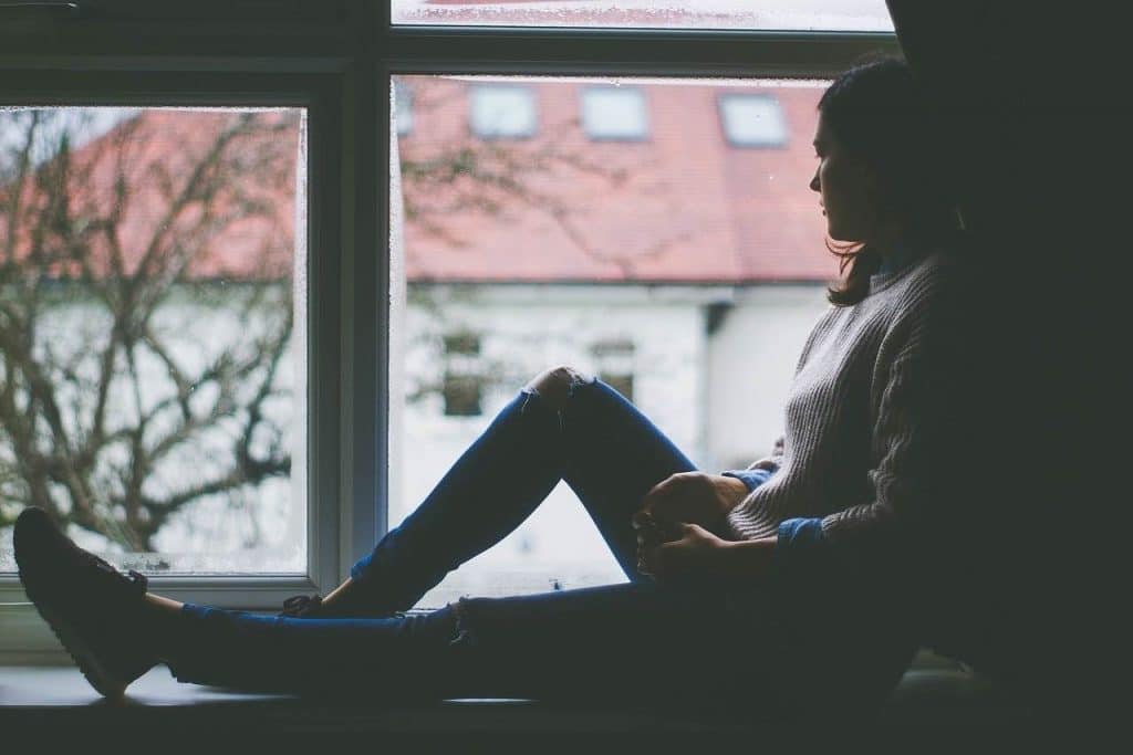 Woman sitting by the windowsill looking pensive