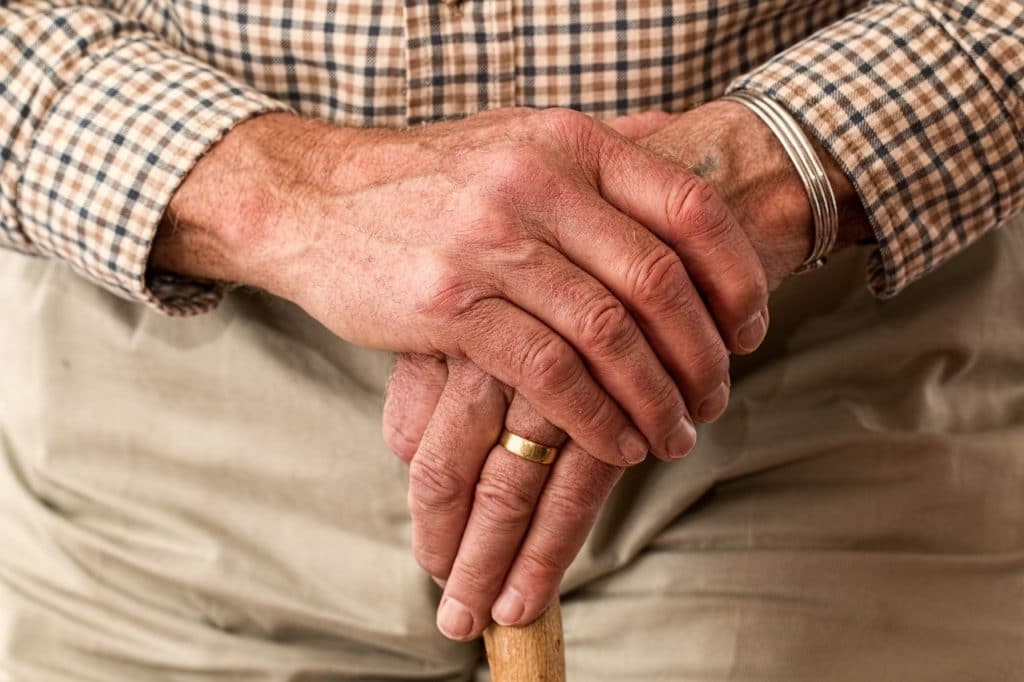 Older man's hands holding a cane