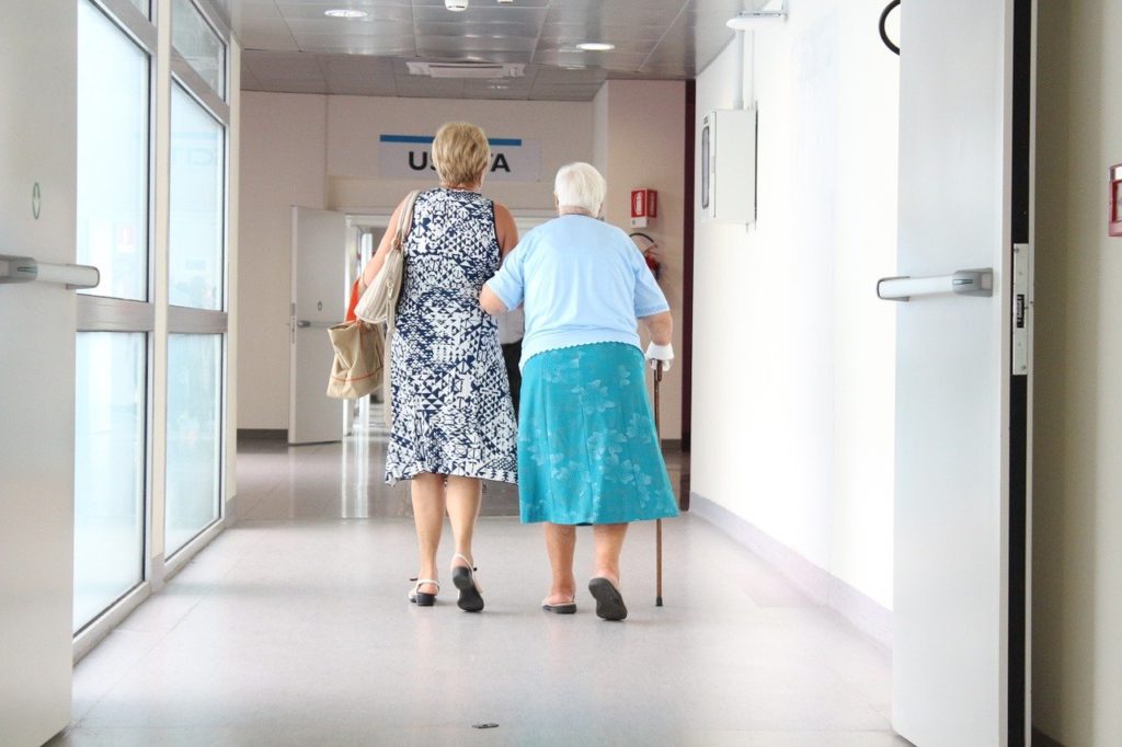 Woman walking with elderly woman in hospital hallway